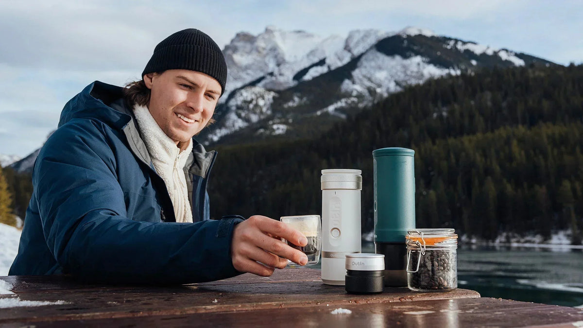 Outdoor coffee brewing with Outin portable espresso machine and accessories at mountain campsite
