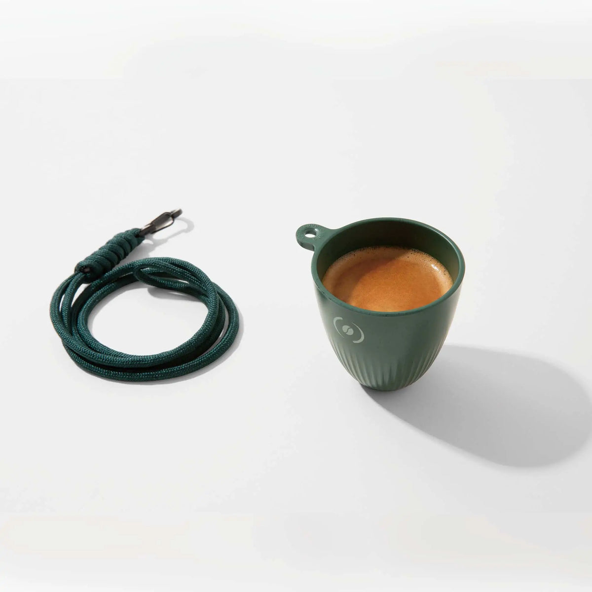 OutIn Rebrew tiefgrüner Espressobecher mit Lanyard, gefüllt mit Espresso, aus recyceltem Kaffeesatz.