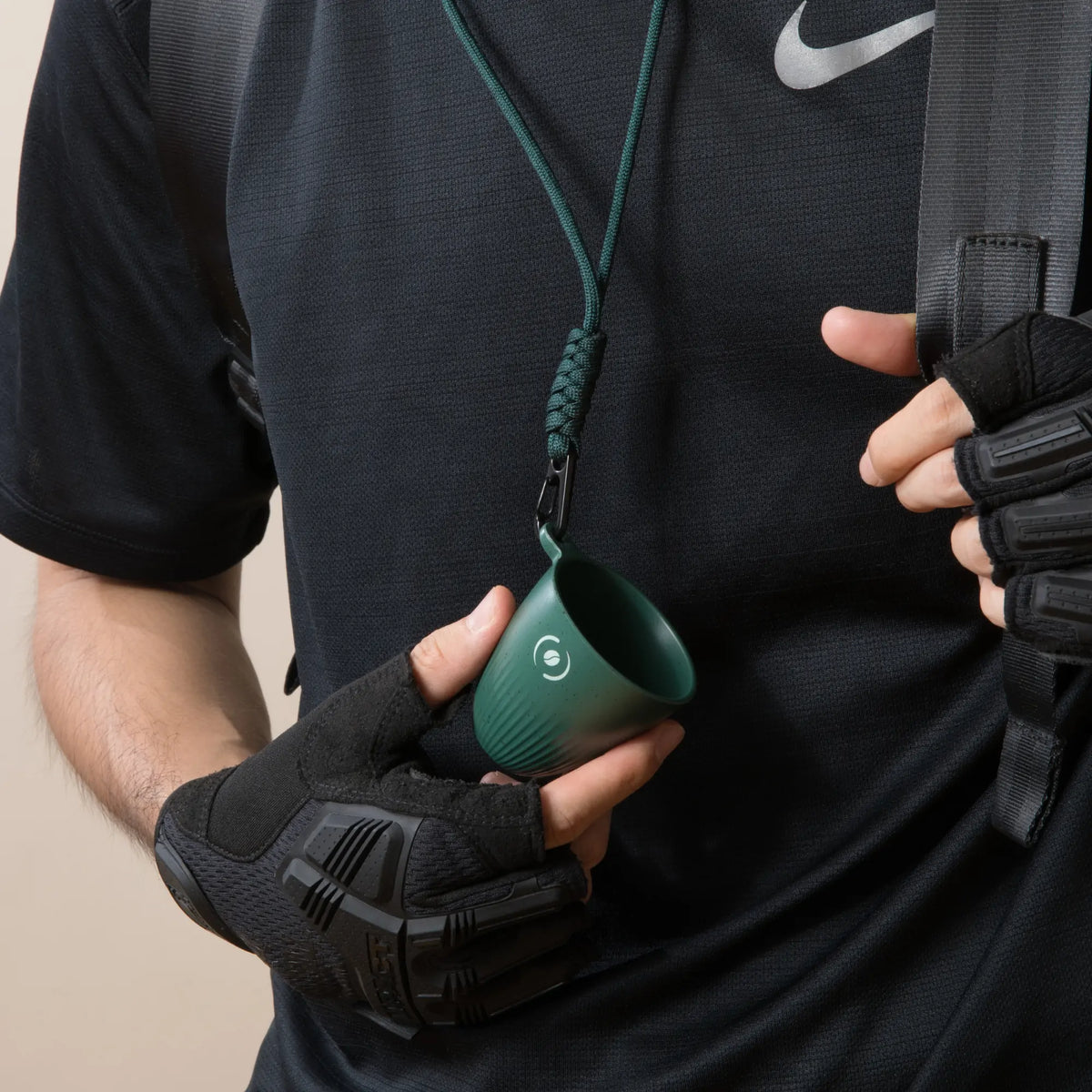 Mann mit OutIn Rebrew tiefgrünem Espressobecher mit Lanyard, ideal für Outdoor-Abenteuer.