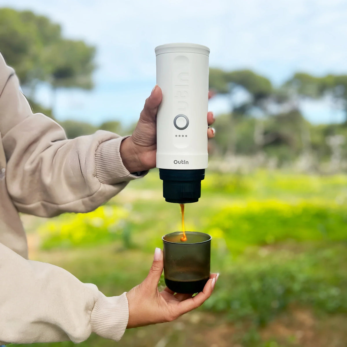 Perlweiße OutIn Nano Espressomaschine brüht Espresso im Freien in einen dunklen Becher.