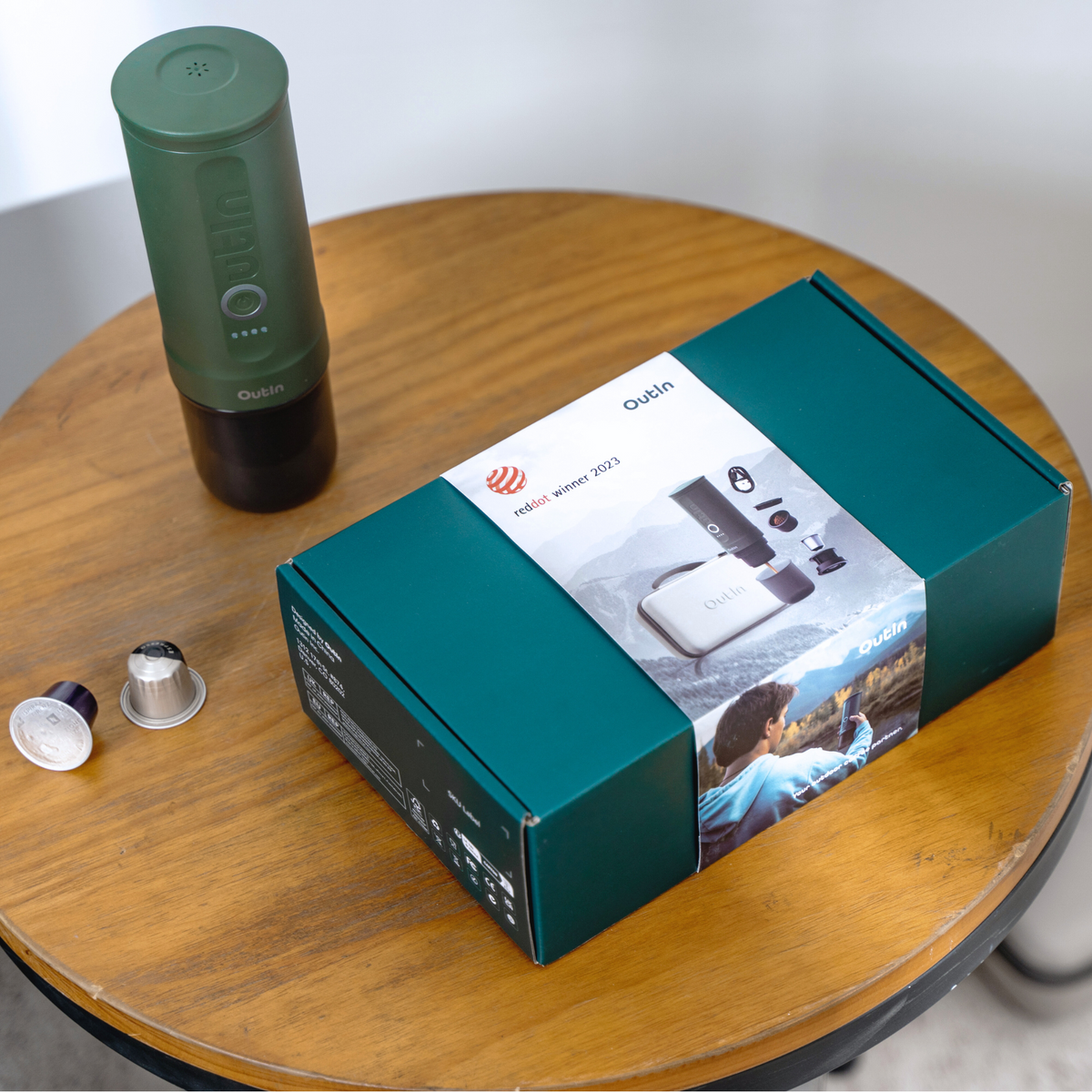 Waldgrünes OutIn Reise-Espressogerät Geschenkset mit Red Dot Award-Siegel auf Holztisch.