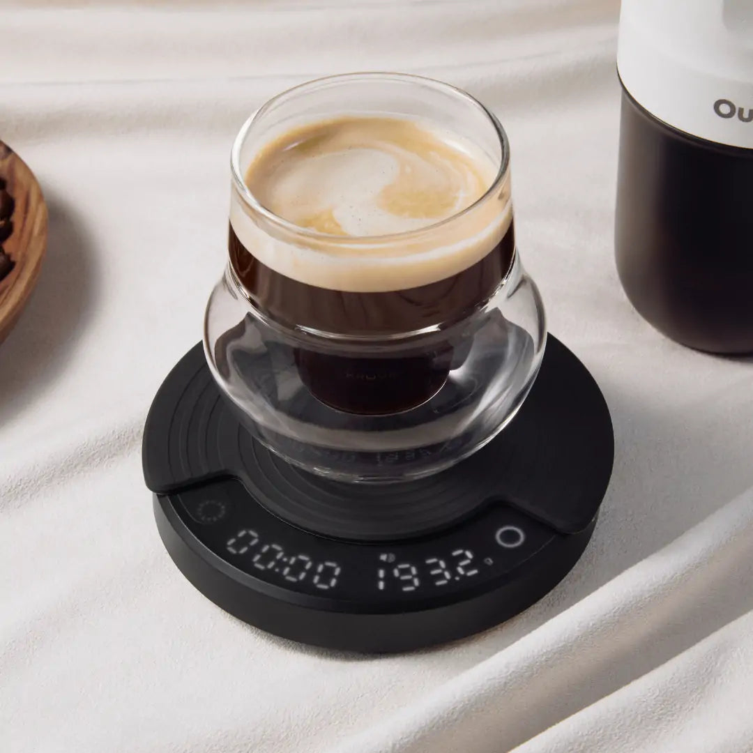 Schwarze OutIn Claro Kaffeewaage mit Espresso-Glas und Anzeige von 00:00 / 193.2g beim Brühen.