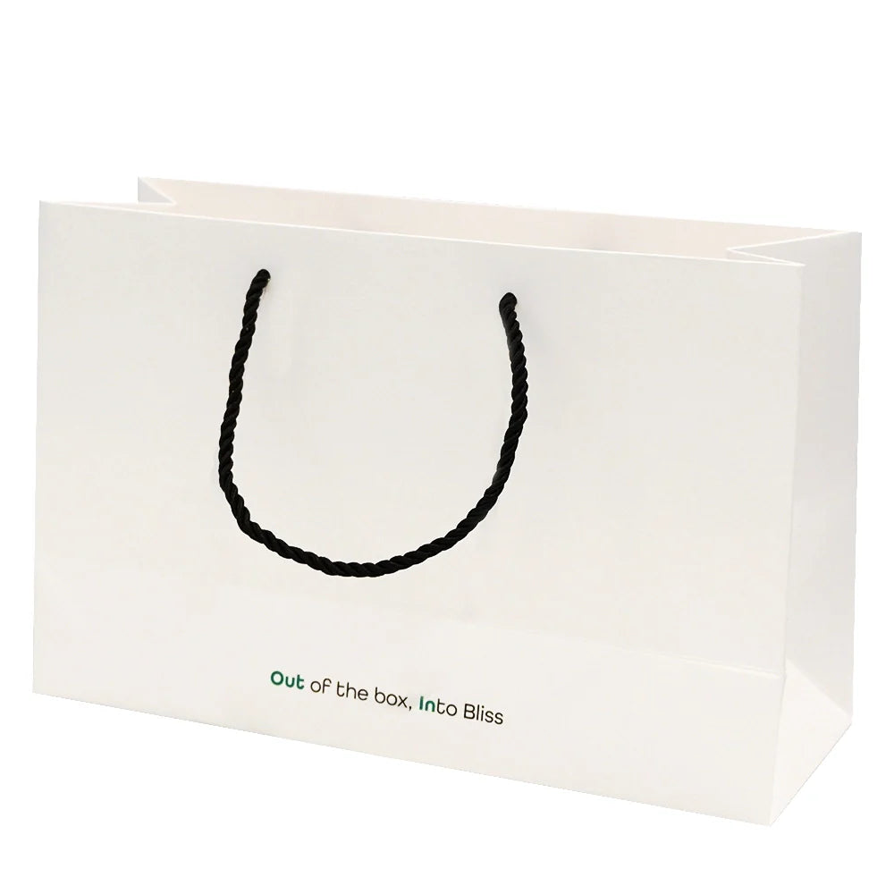 Weiße Geschenktasche mit Kordelgriffen und Aufschrift „Out of the box, Into Bliss“, ideal für tragbare Espressomaschinen.