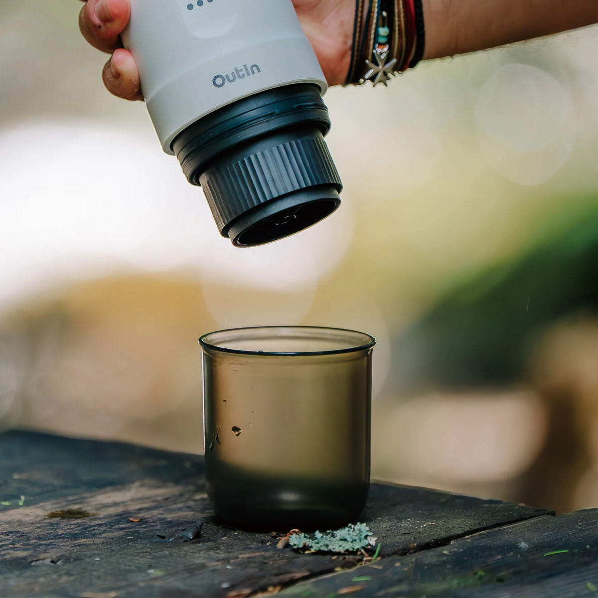 Rauchfarbener Kunststoffbecher für Nano Espressomaschine wird im Freien befüllt, ideal für unterwegs.