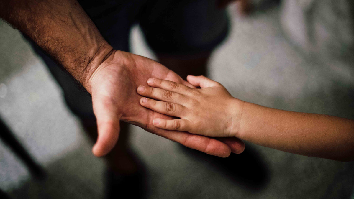 Erwachsene und Kinderhand berühren sich – Symbol für Vertrauen, Fürsorge und familiäre Unterstützung﻿