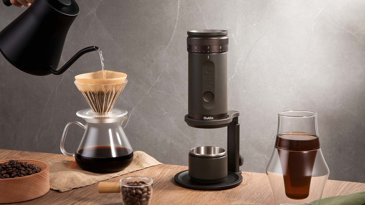 Manuelle Kaffe Zubereitung mit Aufgussmethode, bestehend aus Outin-Kaffeemühle, Glaskaraffe und frisch gemahlenem Kaffee auf dem Tisch – ein Spezialitätenkaffee-Zubereitungsprozess.