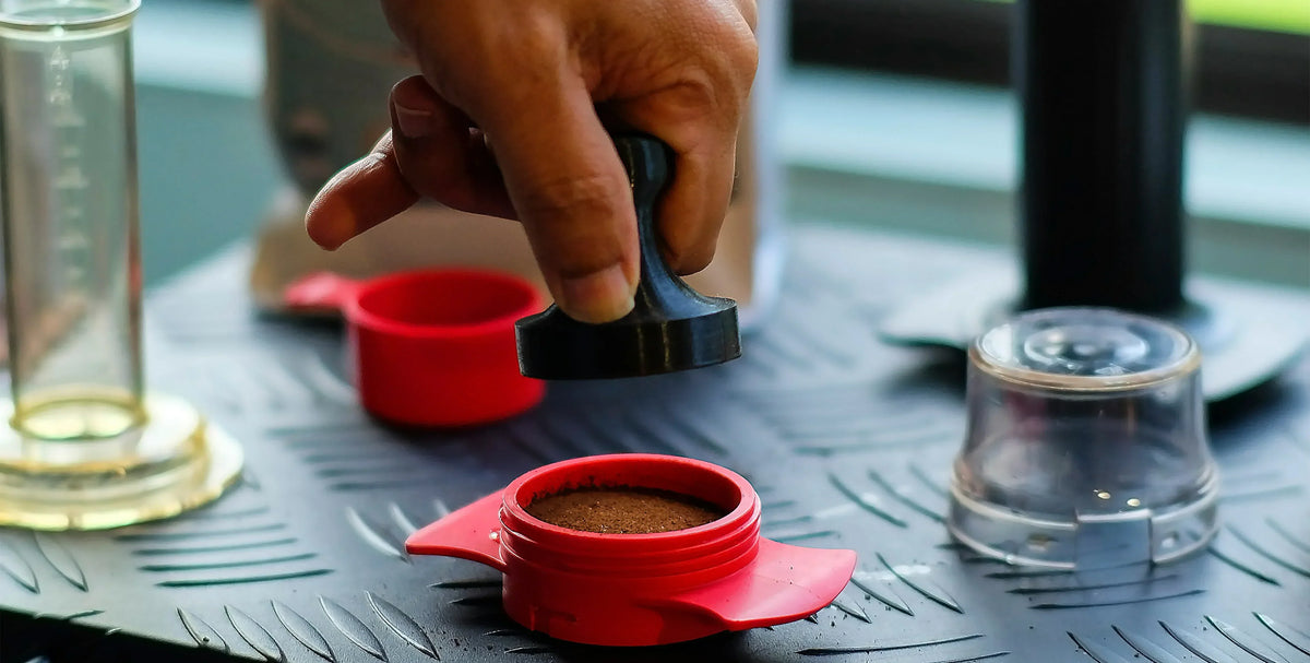 A barista expertly tamping down freshly ground coffee in a portafilter, preparing a rich espresso shot.