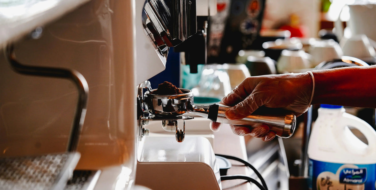 A barista expertly grinds fresh coffee beans into a portafilter, preparing the perfect espresso shot.