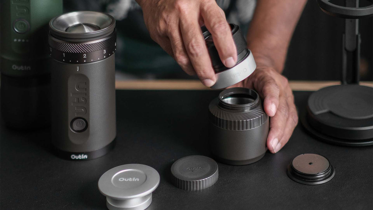 Hände beim Zusammenbau der tragbaren elektrischen Kaffeemühle von Outin, um frisches Mahlgut für einen perfekten Espresso-Shot vorzubereiten
