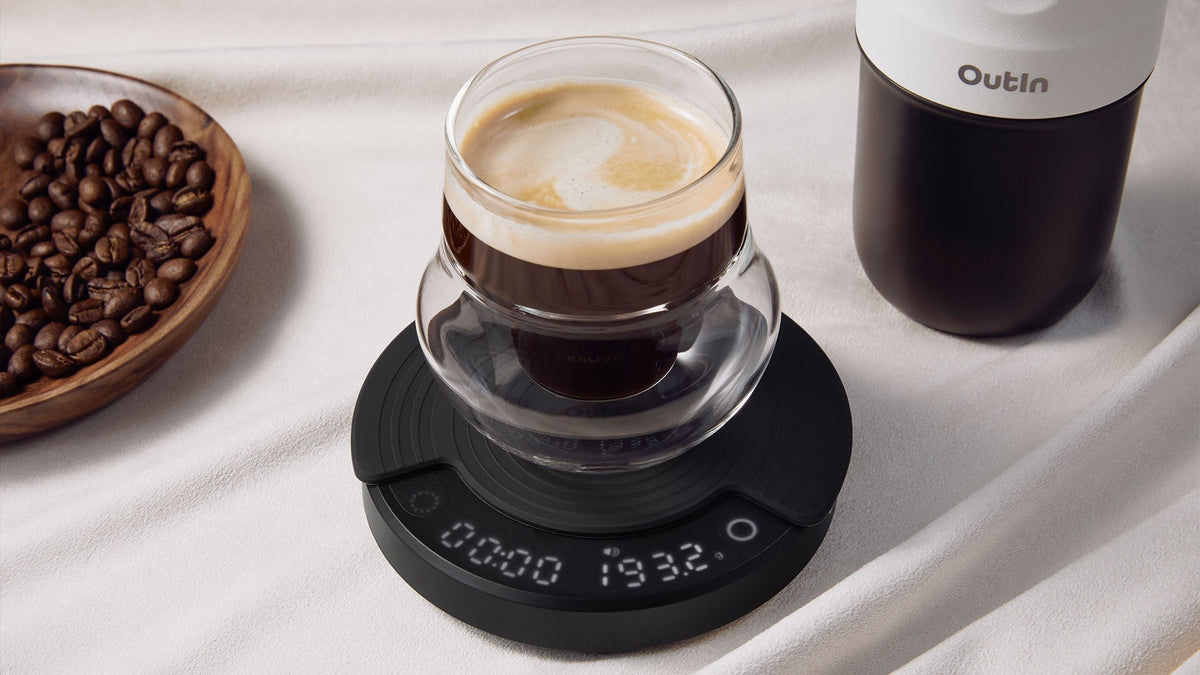 Outln Kaffeebrühsystem mit digitaler Waage, die präzise Messwerte für ein optimales Kaffee-Wasser-Verhältnis anzeigt, dazu frisch gebrühter Kaffee mit Crema und ganze Bohnen in der Nähe