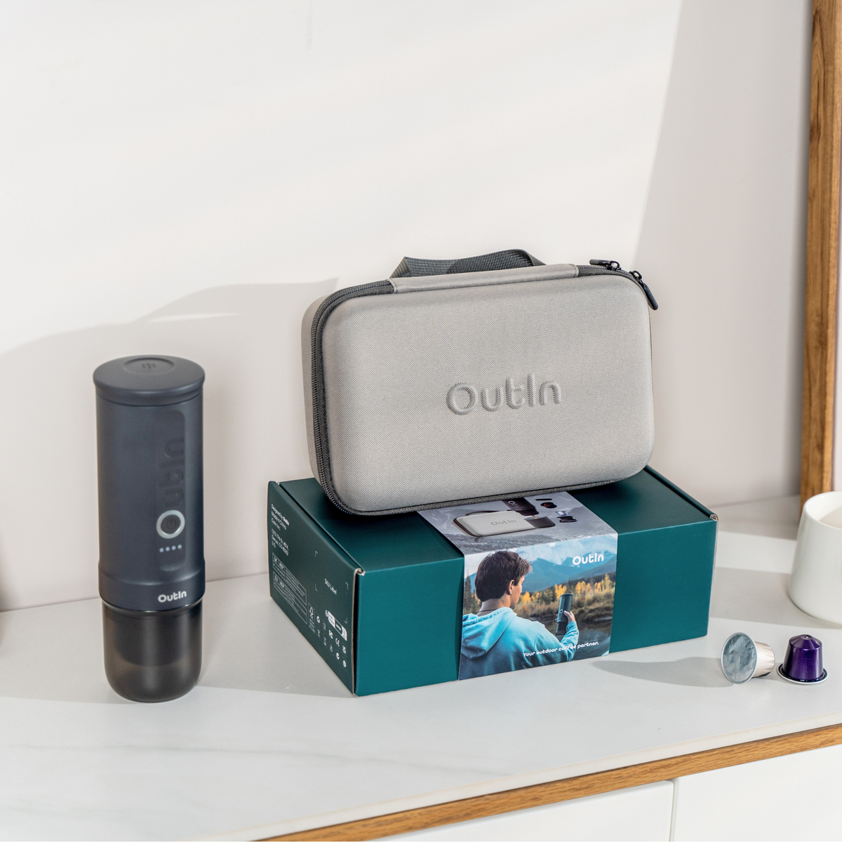 OutIn Espresso-Geschenkset Space Grau: Gerät, Hülle und Verpackung mit Kaffeekapseln im Lieferumfang.