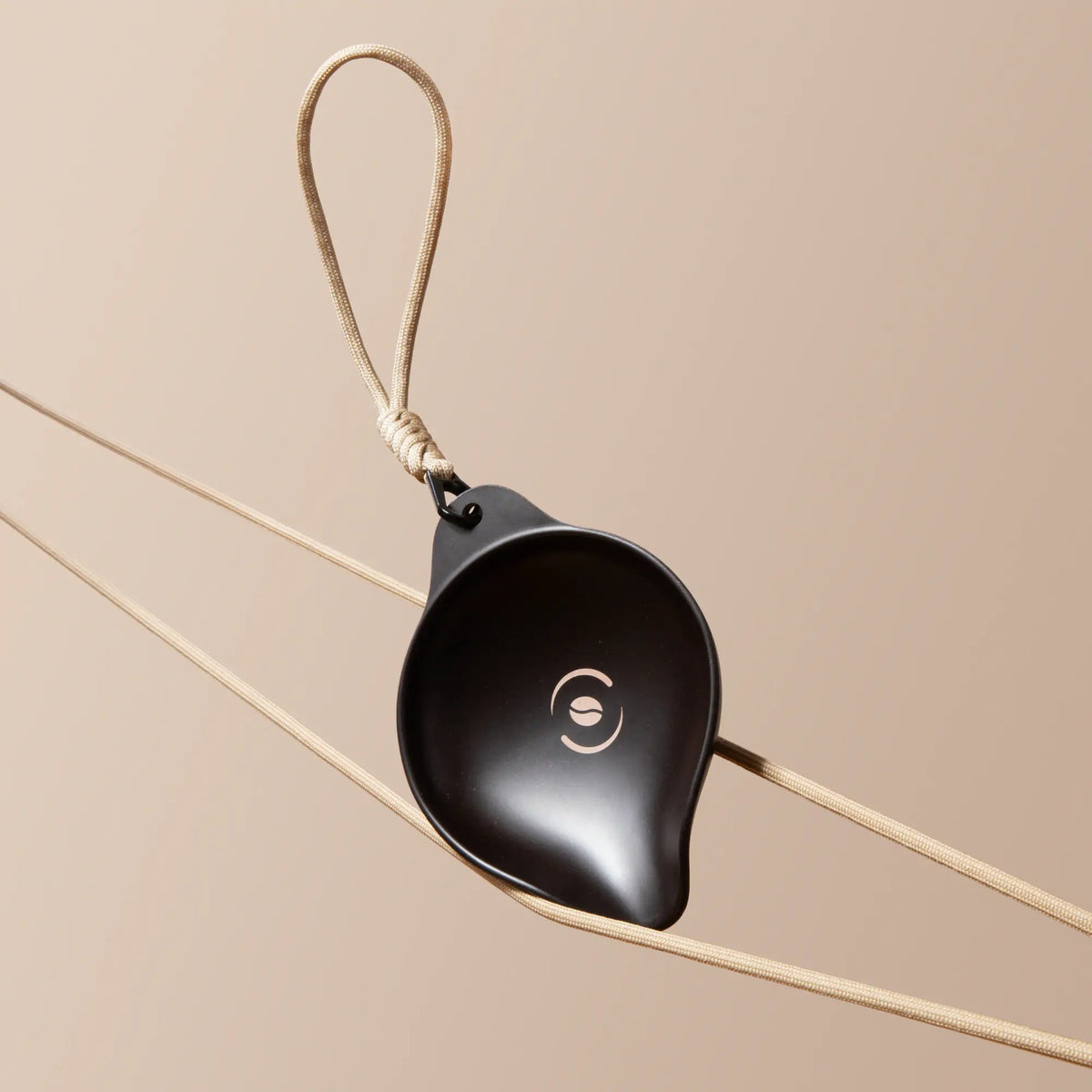 OutIn Rebrew Bohnen-Tablett, dunkelbraun aus recyceltem Kaffeesatz, mit Kaffeebohnen-Logo und beigem Lanyard für Kaffeezubereitung.