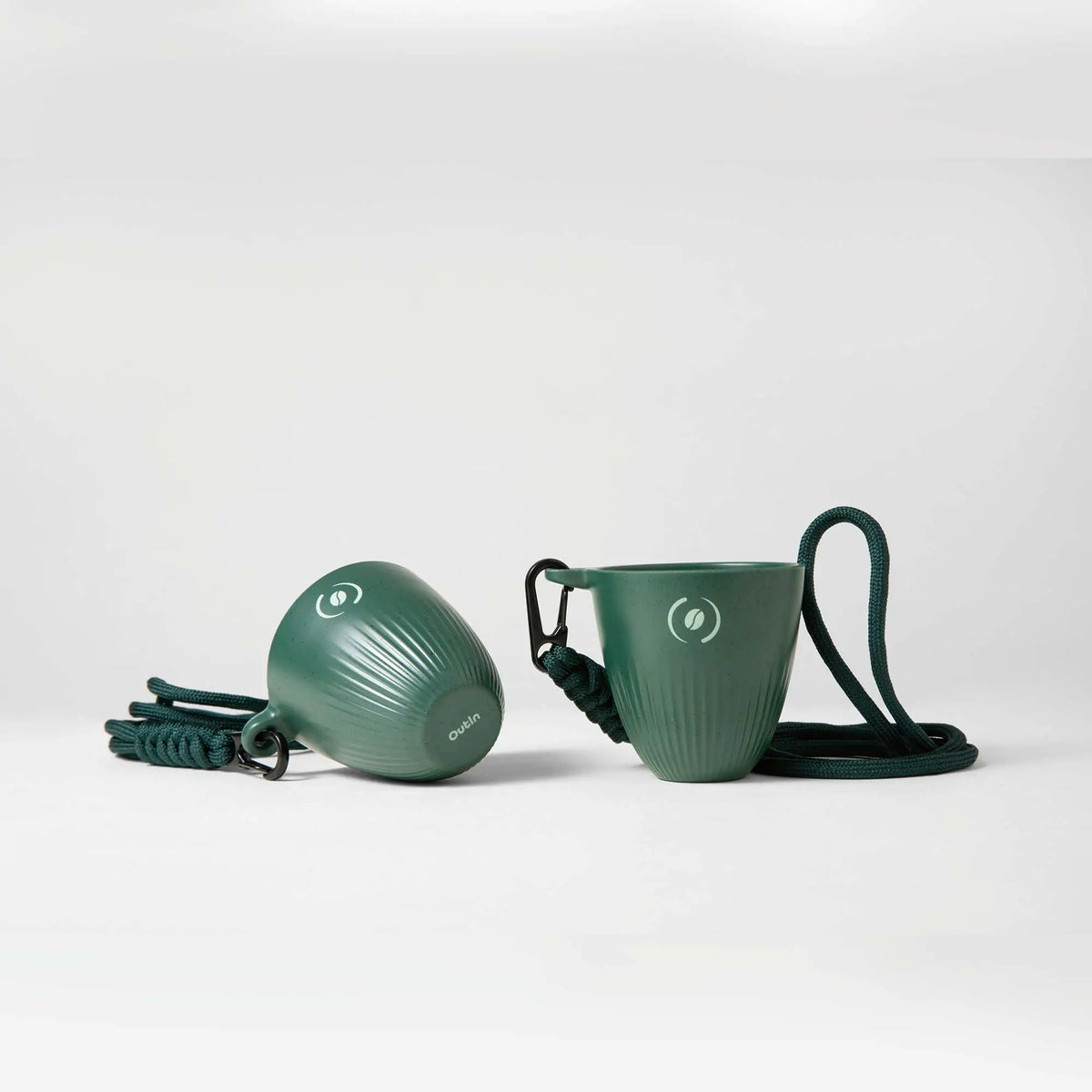 Zwei tiefgrüne OutIn Rebrew Espresso Becher aus Melaminharz und recyceltem Kaffeesatz, mit geriffelter Textur und Lanyard.