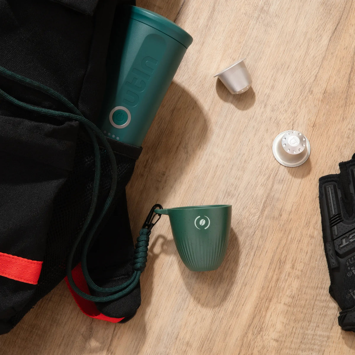 OutIn Rebrew Espresso Becher tiefgrün mit Lanyard und OutIn Nano Maschine, Kaffeekapseln und Handschuh für Outdoor-Einsatz.