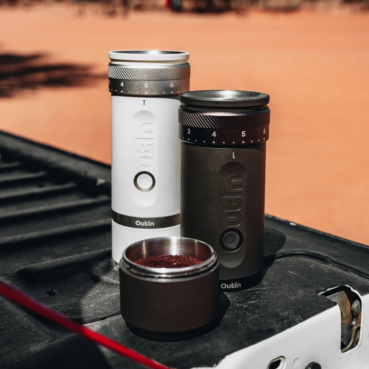 OutIn Fino tragbare Kaffeemühle in Anthrazit und Weiß mit Mahlgradskala, frisch gemahlener Kaffee im Behälter.