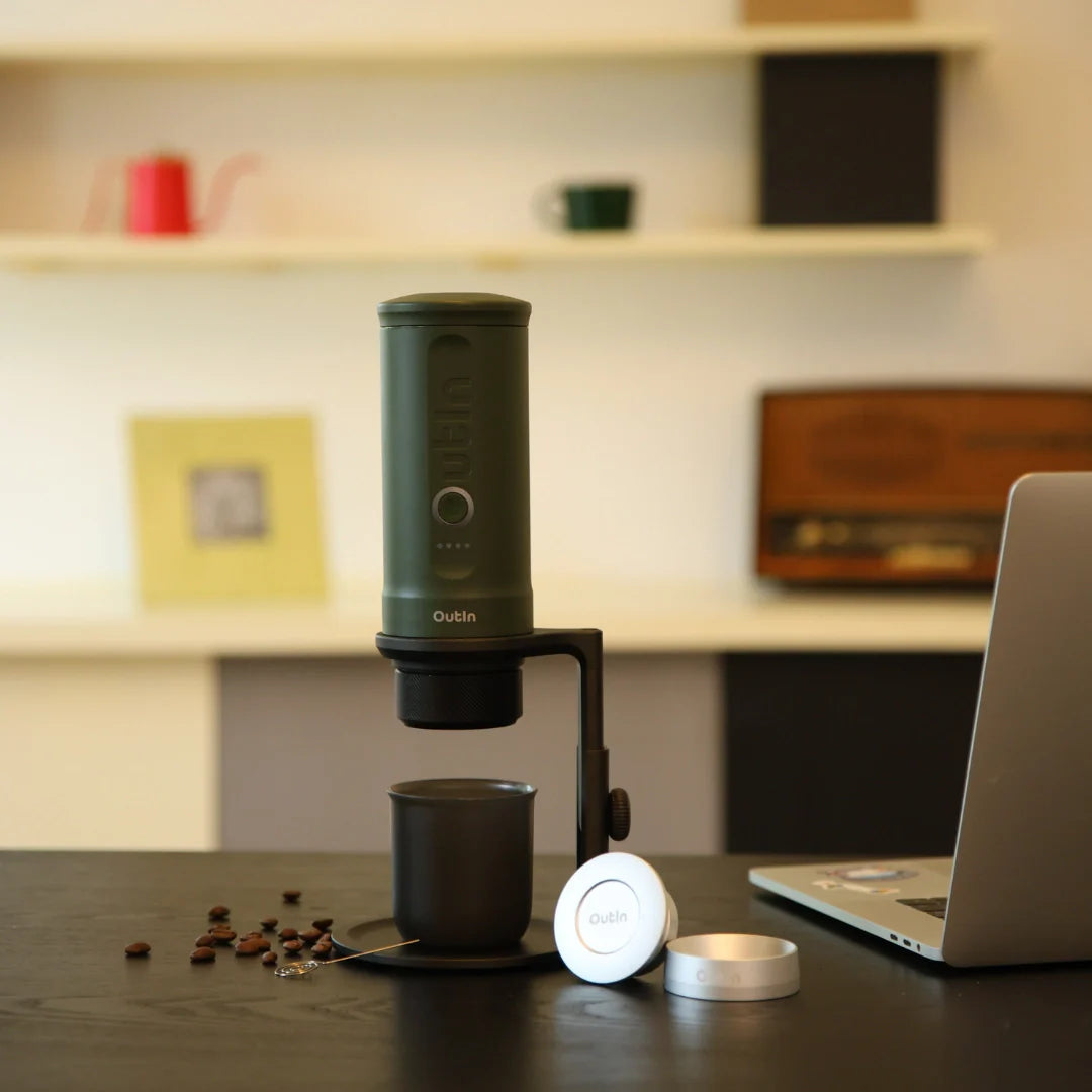 Universeller Kaffeeständer aus Aluminium, höhenverstellbar, mit Korkuntersetzer, hält Kaffeebereiter über Tasse, neben Laptop.