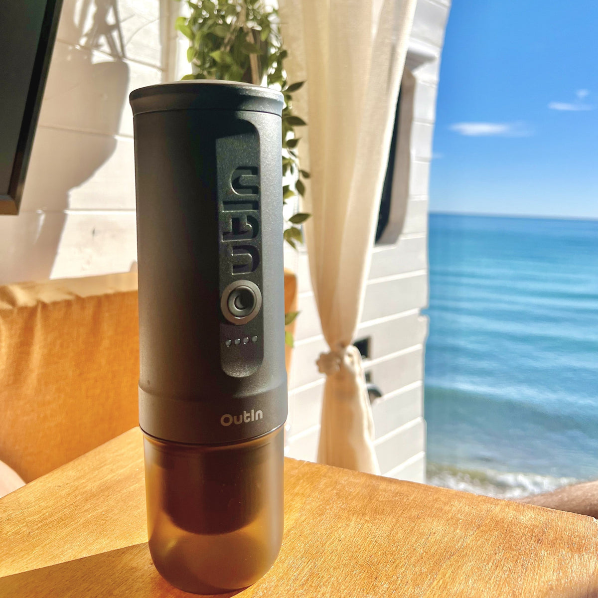 Nano tragbare Espressomaschine in Space Grau, perfekt für Kaffee am Meer. Mit OutIn-Logo, ideal für unterwegs.