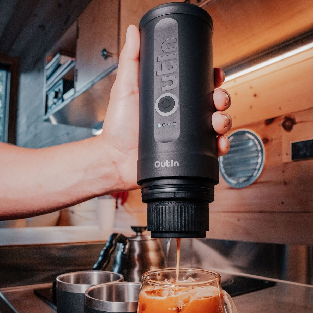 Nano Tragbare Espressomaschine in Space Grau brüht Espresso in ein Glas mit Eiswürfeln.