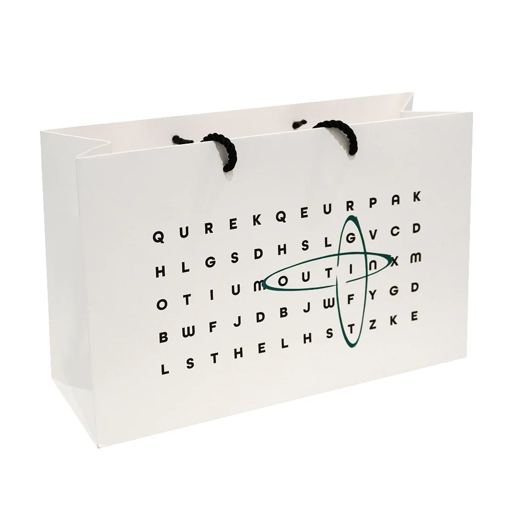 Weiße Geschenktasche für tragbare Espressomaschine mit Wortsuchrätsel-Design und Kordelgriffen.