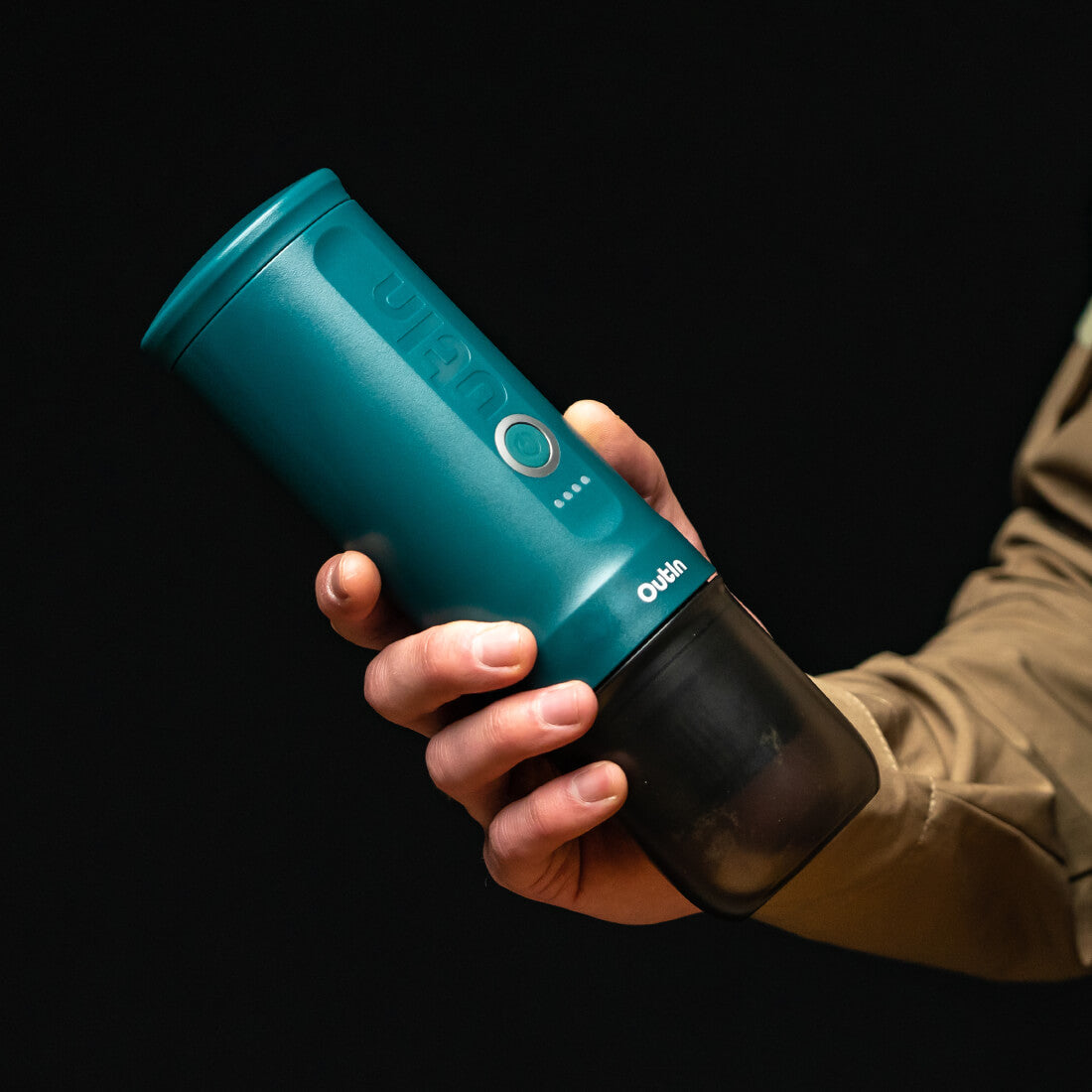Nano Tragbare Espressomaschine Blaugrün in Hand gehalten, zeigt kompaktes Design mit Bedienknopf und Ladeanzeige.